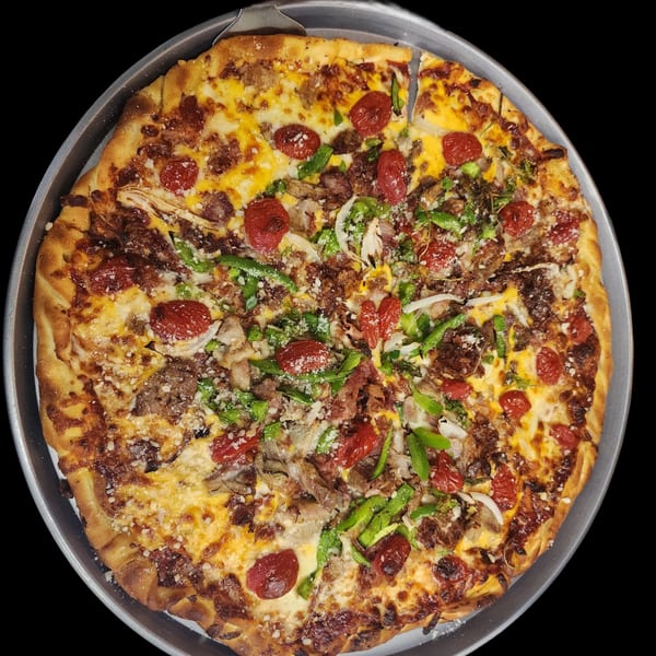 A whole pizza with various toppings including tomatoes, green peppers, and meat, in a metal pan.